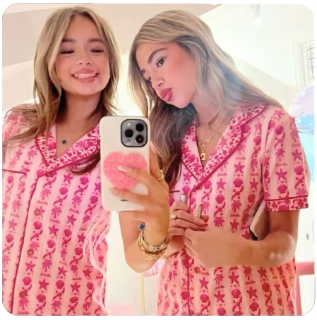 Two women in pink pajamas taking a mirror selfie.